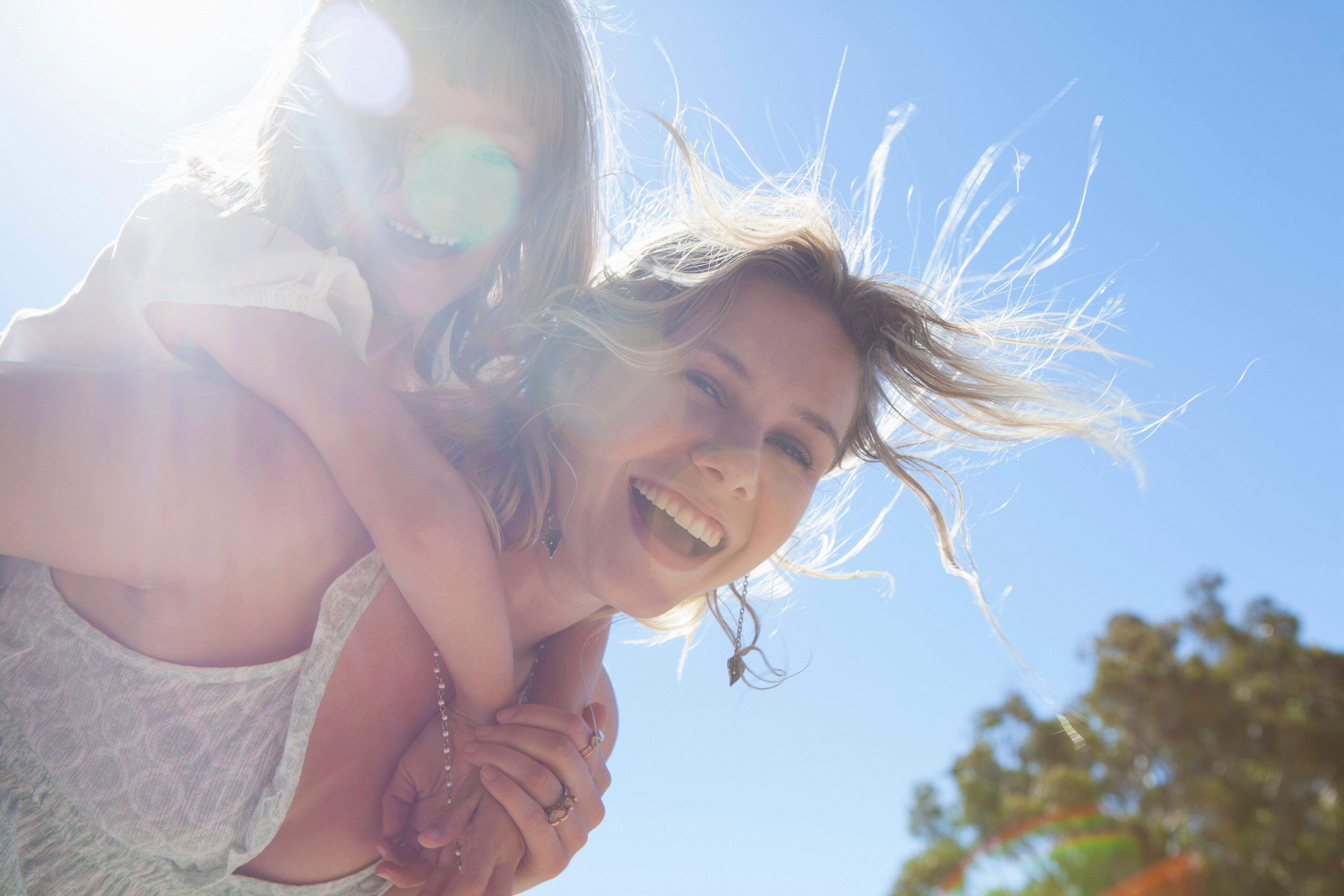 Glückliche Frau trägt lachendes Mädchen Huckepack